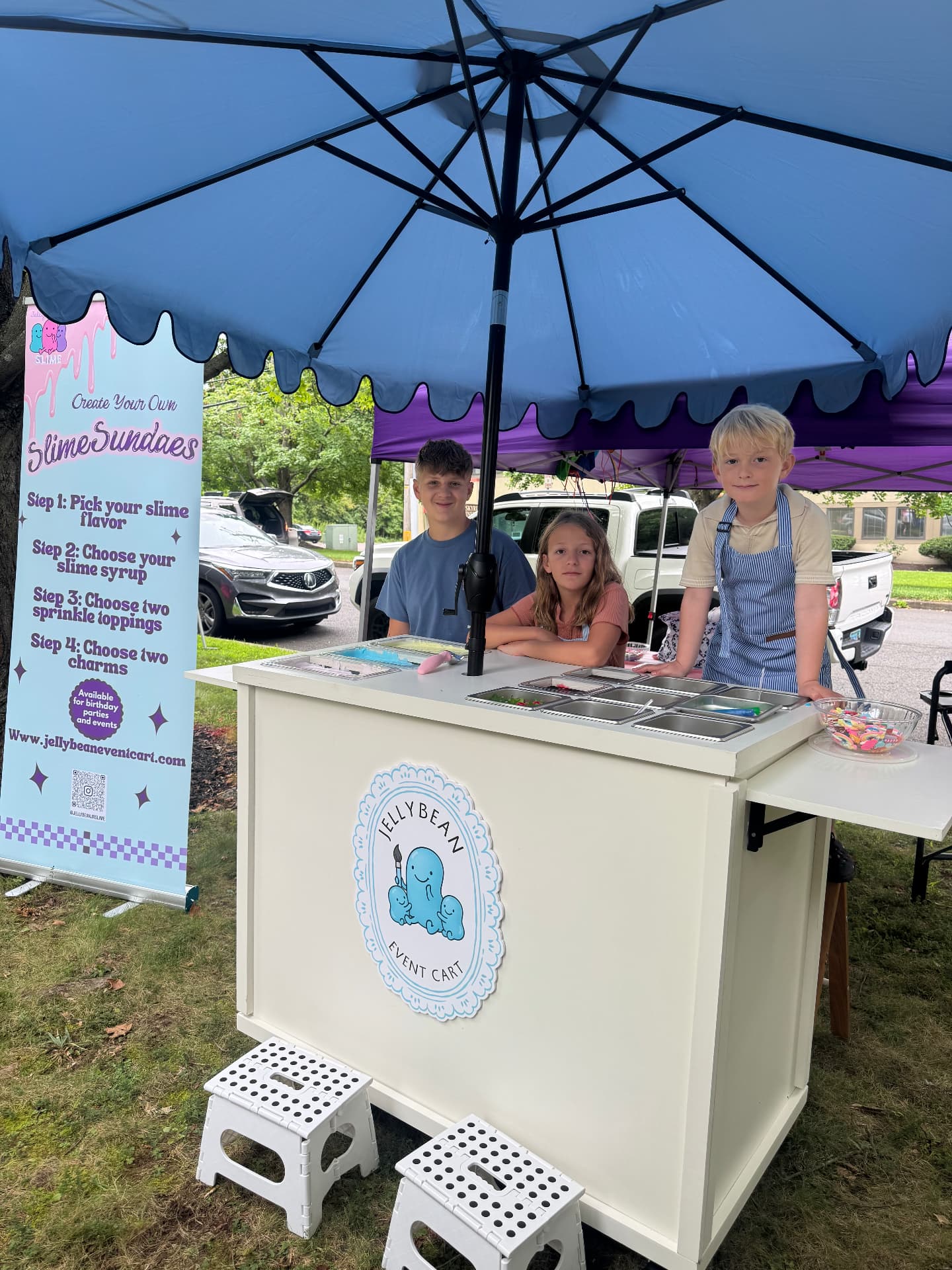 Kids having fun at the Jellybean Event Cart, decorated with a big blue umbrella and slime sundae banner